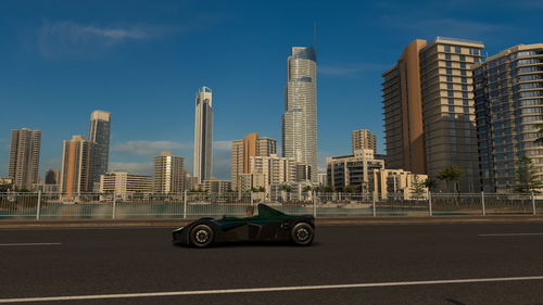 Cars on road by buildings against sky in city