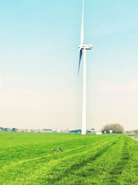 Wind turbines on field against sky