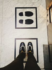 Low section of man standing on tiled floor