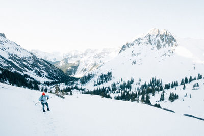 Person skiing on snowcapped mountain against clear sky