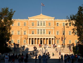 People outside historic building against clear blue sky