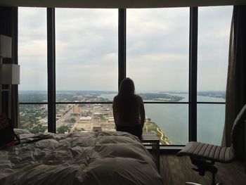 Rear view of woman standing in hotel room against window