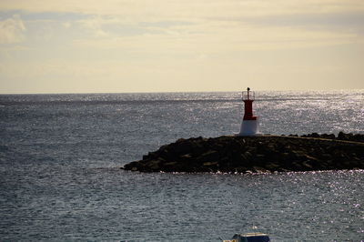 Lighthouse by sea against sky