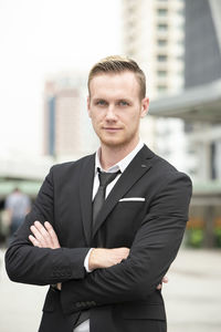 Portrait of man standing against city