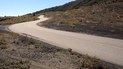 Scenic view of road by volcano against clear sky