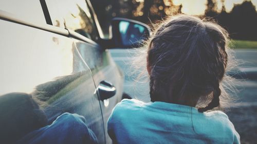 Rear view of girl standing by car