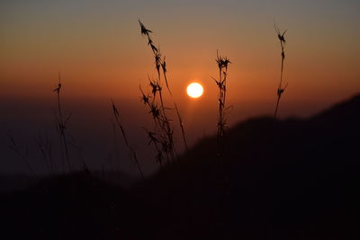 Silhouette landscape against orange sky