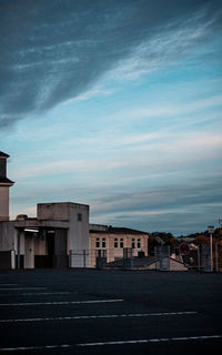 Road by buildings against sky at dusk