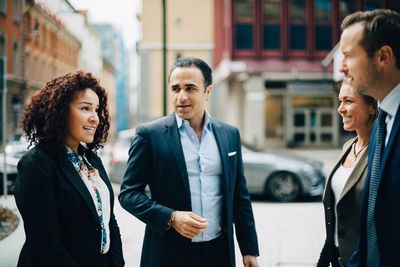 Smiling business colleagues talking while standing in city