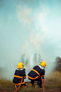 Firefighters spraying water while crouching on field 