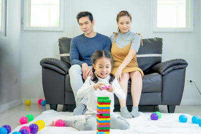 Full length of friends sitting on sofa