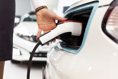 Cropped hand of woman filling fuel in car