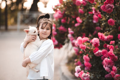 Smiling baby girl holding pet dog over nature background close up. looking at camera.