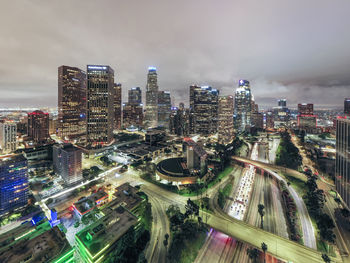 High angle view of illuminated street amidst buildings against sky