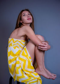 Portrait of young woman standing against gray background