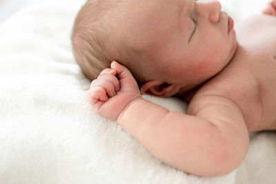 Low section of newborn sleeping on bed at home