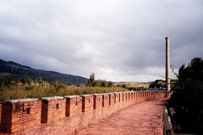 Footpath against cloudy sky