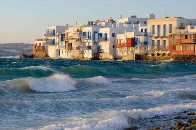 Sea by buildings against sky