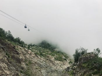 Low angle view of overhead cable car against sky