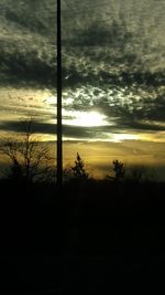 Silhouette trees on landscape against sky at sunset