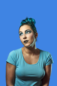 Portrait of young woman against blue background