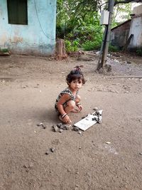 Portrait of cute girl playing with rocks on road