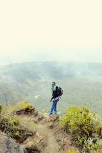 Man standing on mountain against sky during foggy weather