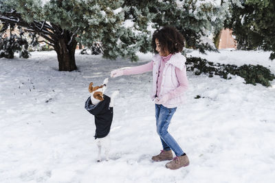 Cute afro girl playing with dog in snow at park