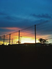 Silhouette fence against sky during sunset