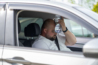 Side view of man using mobile phone in car