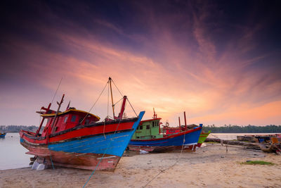 Boats moored at beach during sunset