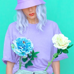 Midsection of woman with pink flowers against colored background