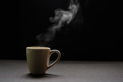 Close-up of coffee cup on table against black background