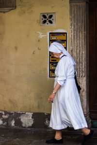 Side view of nun walking by wall