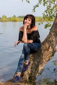 A beautiful female tourist resting sitting on a tree near the river.