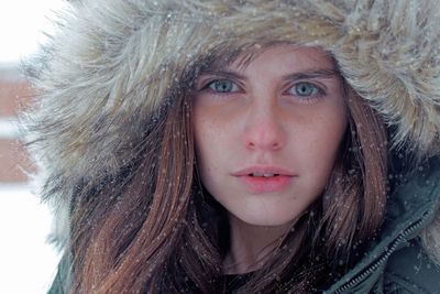 Close-up portrait of beautiful woman wearing fur coat during snowfall