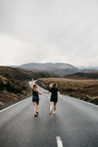 Friends walking on road against sky