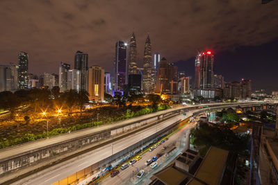 Illuminated city by buildings against sky at night