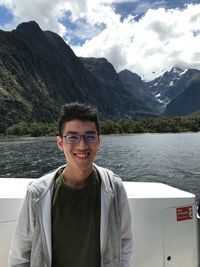 Portrait of smiling man in boat against lake and mountains