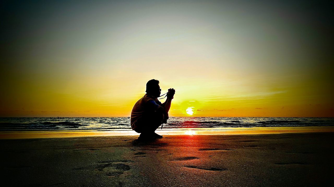 SILHOUETTE OF MAN AT BEACH AGAINST SKY DURING SUNSET