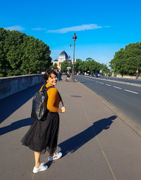 Young woman on umbrella in city against sky