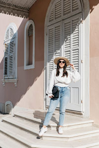 Full length portrait of woman standing against building