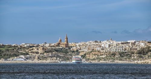 Buildings by sea against sky in city