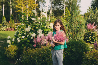 Full length of woman standing by flowering plants