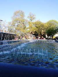 Group of people by swimming pool in city against clear sky