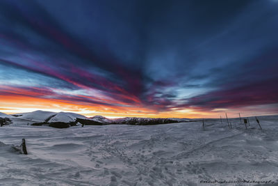 Scenic view of snow covered landscape against sky during sunset