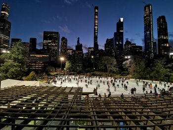 People on illuminated buildings in city at night