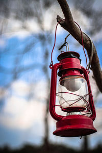 Low angle view of red lantern hanging on branch against sky