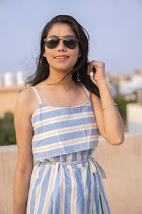 Portrait of young woman wearing sunglasses standing outdoors