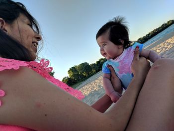 Smiling mother holding daughter at beach